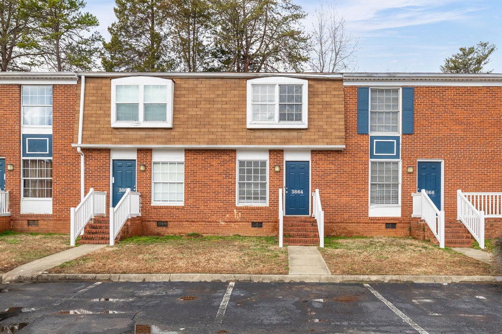 a brick apartment building with blue doors and white stairs