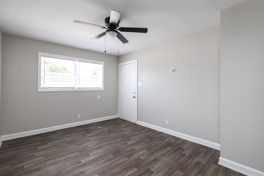 an empty living room with a ceiling fan and a window