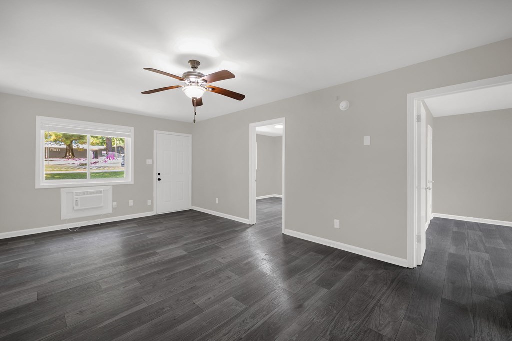 A room with a ceiling fan and a window overlooking a street.