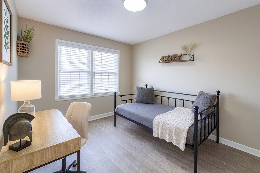 A bedroom with a bed, chair, and desk.