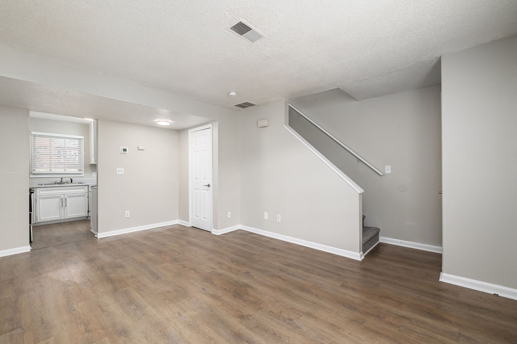 the living room and kitchen of an empty house with wood flooring