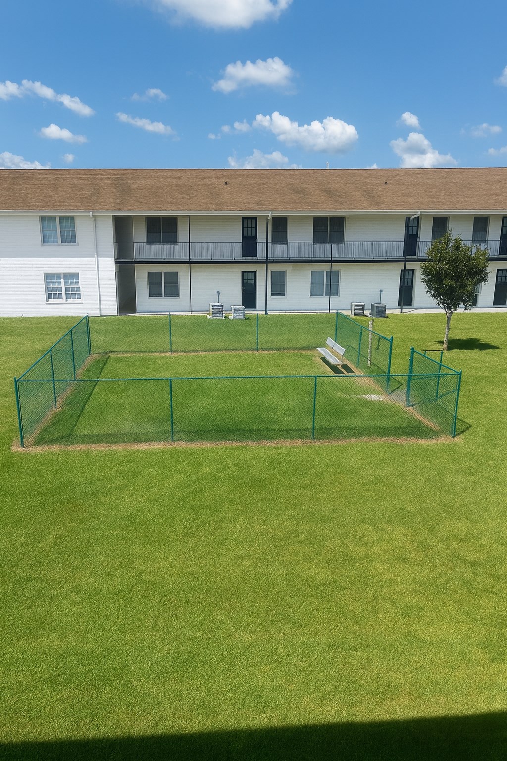 A grassy field with a fence and a building in the background.