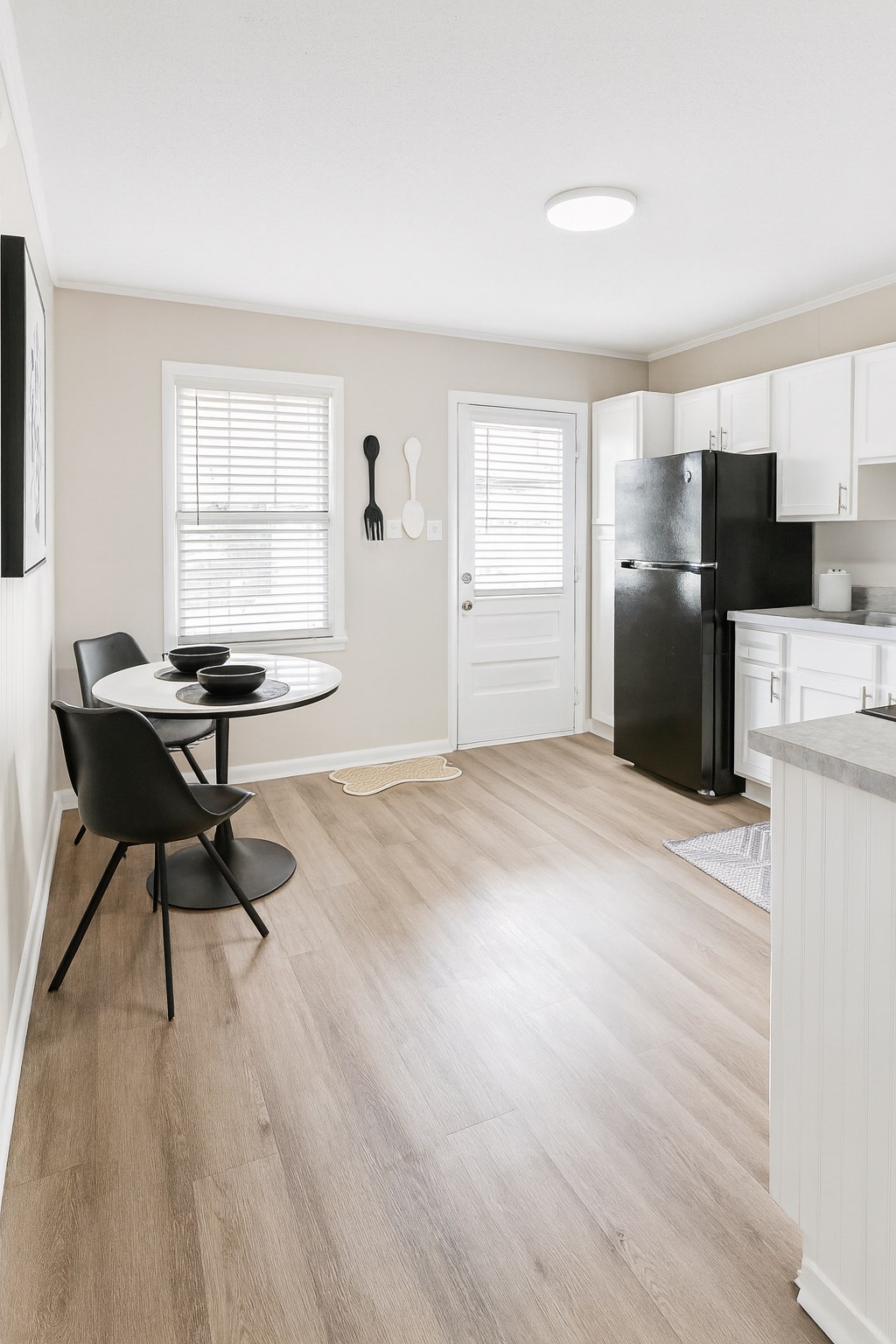 A kitchen with a black fridge and a dining table with two chairs.
