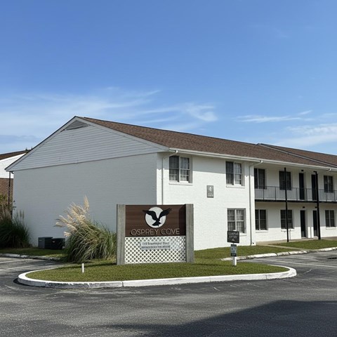 A white building with a sign that says "Osprey Cove" in front of it.