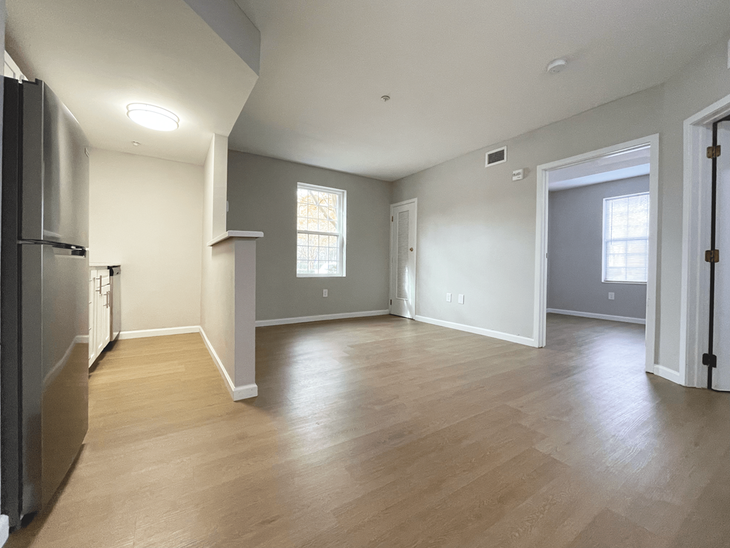 A kitchen with a refrigerator and a dining area with a table and chairs.