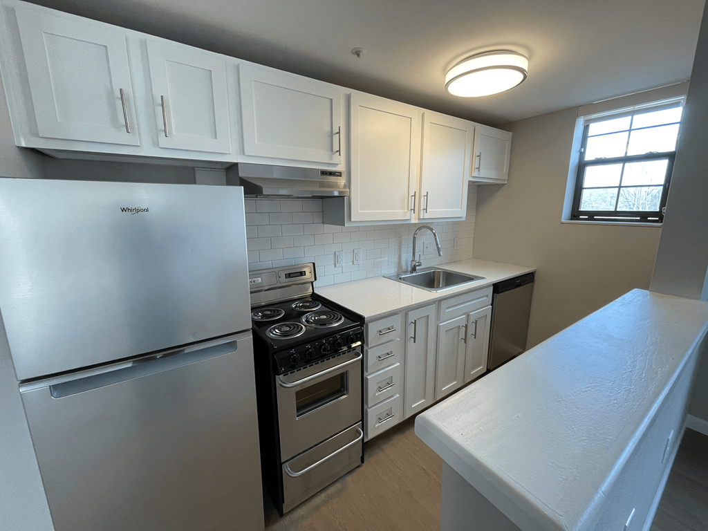 A kitchen with white cabinets and a stainless steel refrigerator.