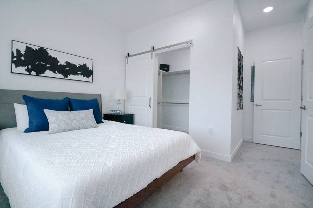 a white bedroom with a large bed and a closet
