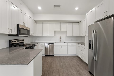 A modern kitchen with white cabinets and stainless steel appliances.