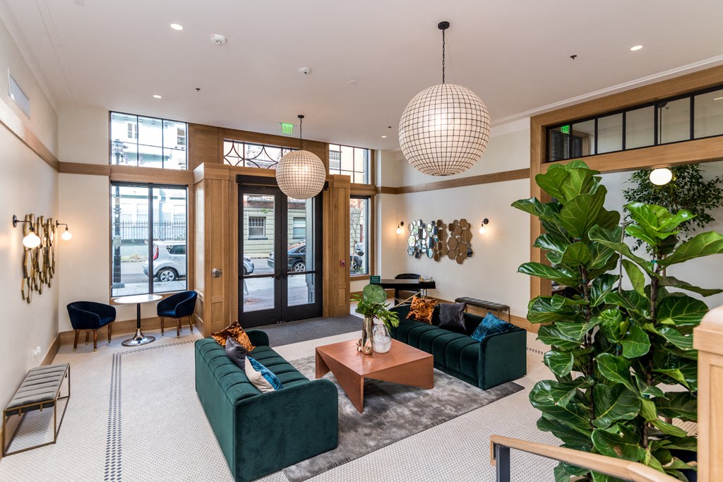 a living room with green couches and a large potted plant
