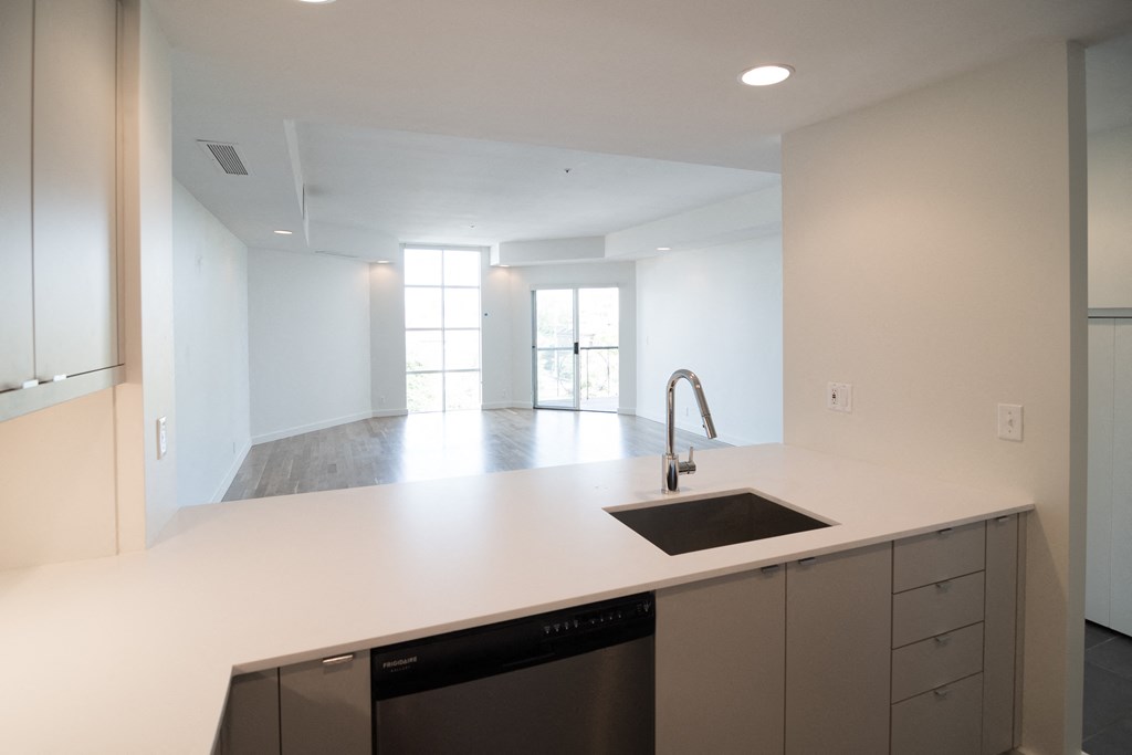 an empty kitchen with white counter top and a sink