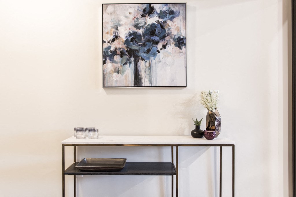 a console table with a vase and a painting on the wall