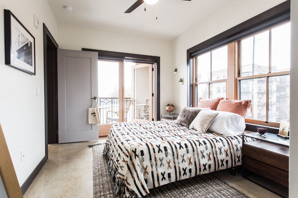 a bedroom with a bed and large windows