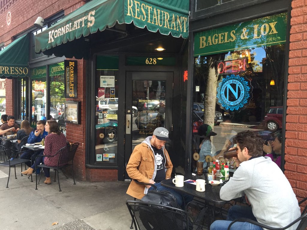 people sitting at tables outside of a restaurant