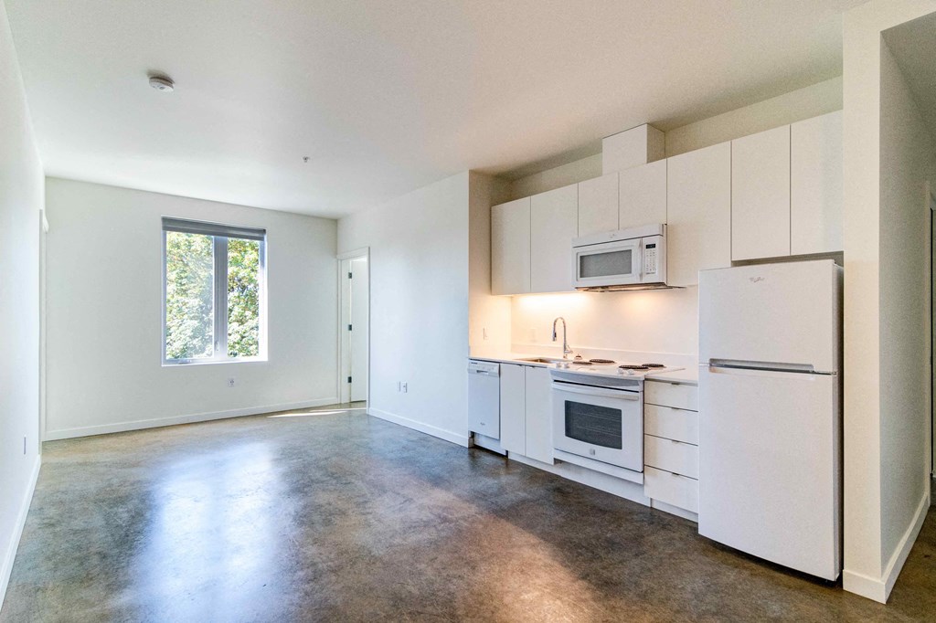 an empty kitchen with white cabinets and a refrigerator