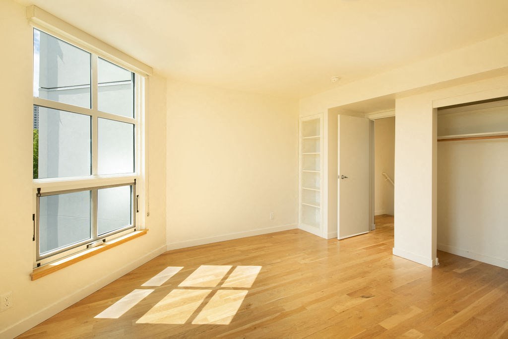 an empty living room with wood floors and a window