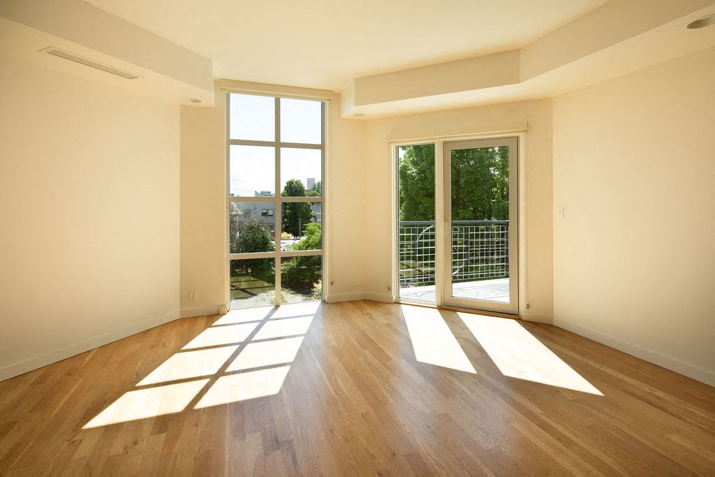 an empty living room with wood flooring and glass doors