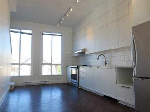 A kitchen with white cabinets and a refrigerator.
