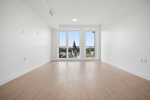 A large empty room with a view of a building outside the window.