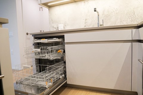 A dishwasher with the door open is in a kitchen.