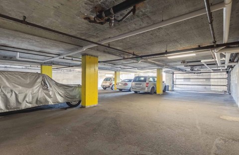 A parking garage with a car parked in front of a yellow pole.