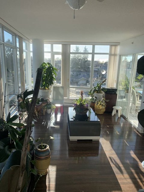 A sunny day in a living room with a large window and a wooden floor.