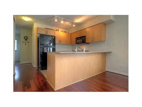A kitchen with wooden cabinets and a black fridge.