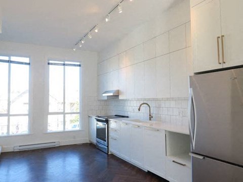 A kitchen with white cabinets and a black fridge.