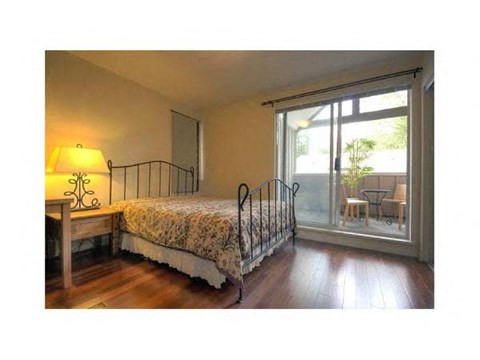 A bedroom with a bed, chair, and lamp.