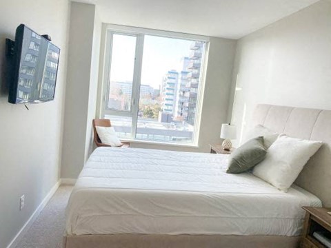 A bedroom with a large bed and a flat screen TV mounted on the wall.