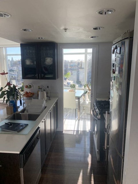 A kitchen with a refrigerator, sink, and a window overlooking a cityscape.