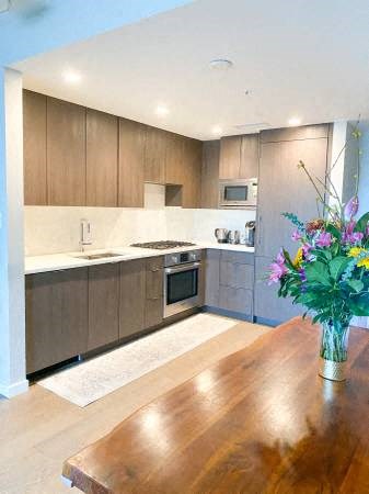 A kitchen with wooden cabinets and a wooden table with a vase of flowers on it.