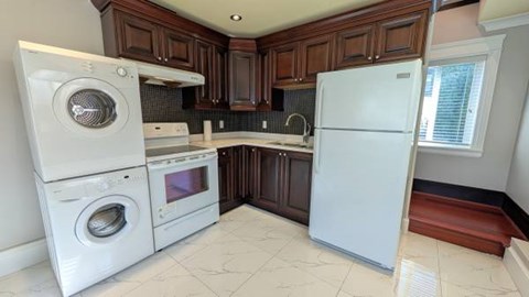 A white washing machine and oven are in a kitchen with dark brown cabinets.