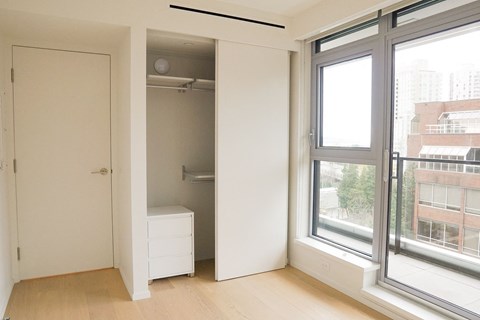 A white bedroom with a large window and a white dresser.