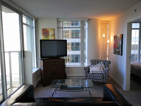 A living room with a black leather couch and a glass coffee table.