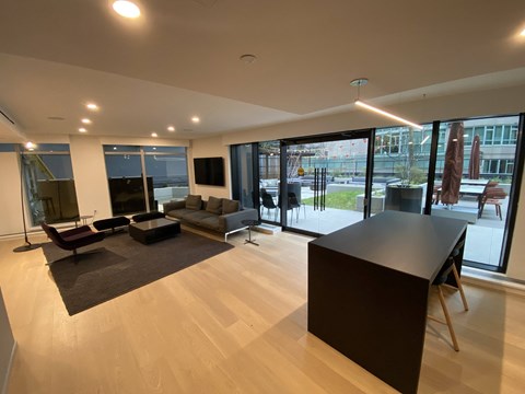 A modern living room with a black sofa and a wooden floor.