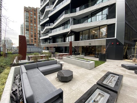 A modern outdoor seating area with a bench and a table in front of a building.