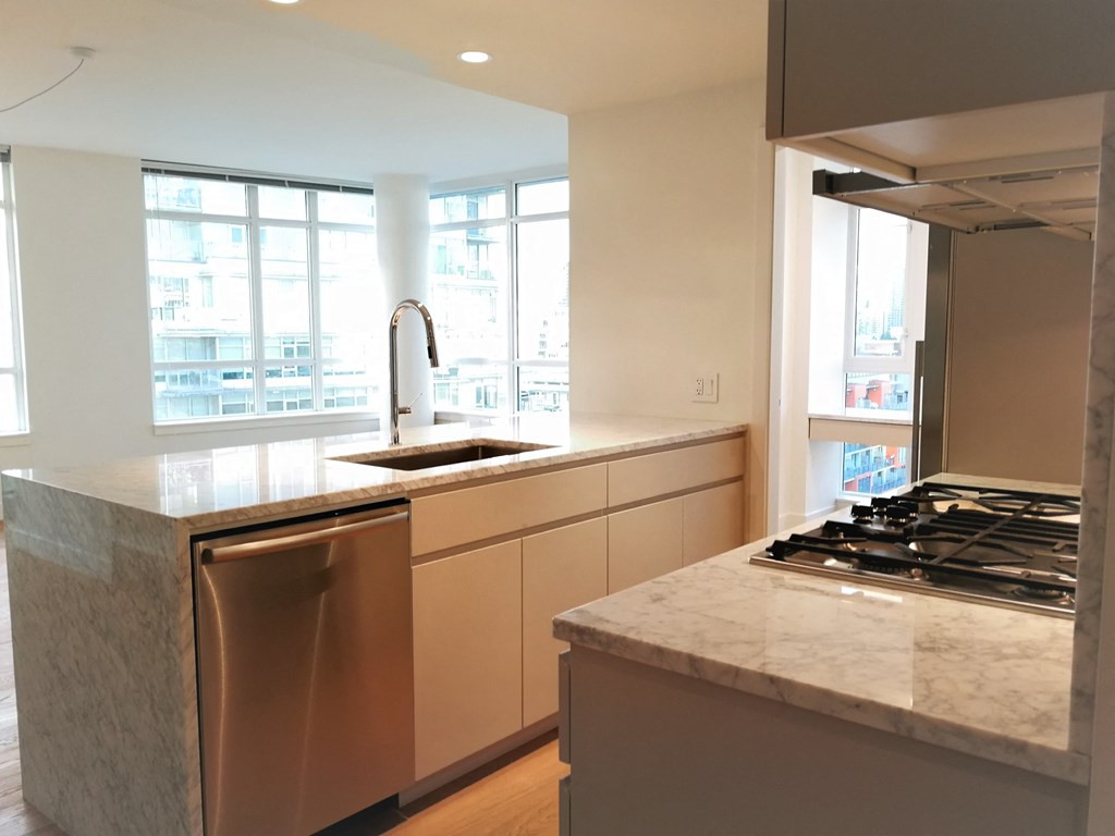 a kitchen with marble counter tops and stainless steel appliances and a large window