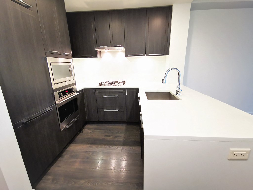 a small kitchen with white countertops and black cabinets