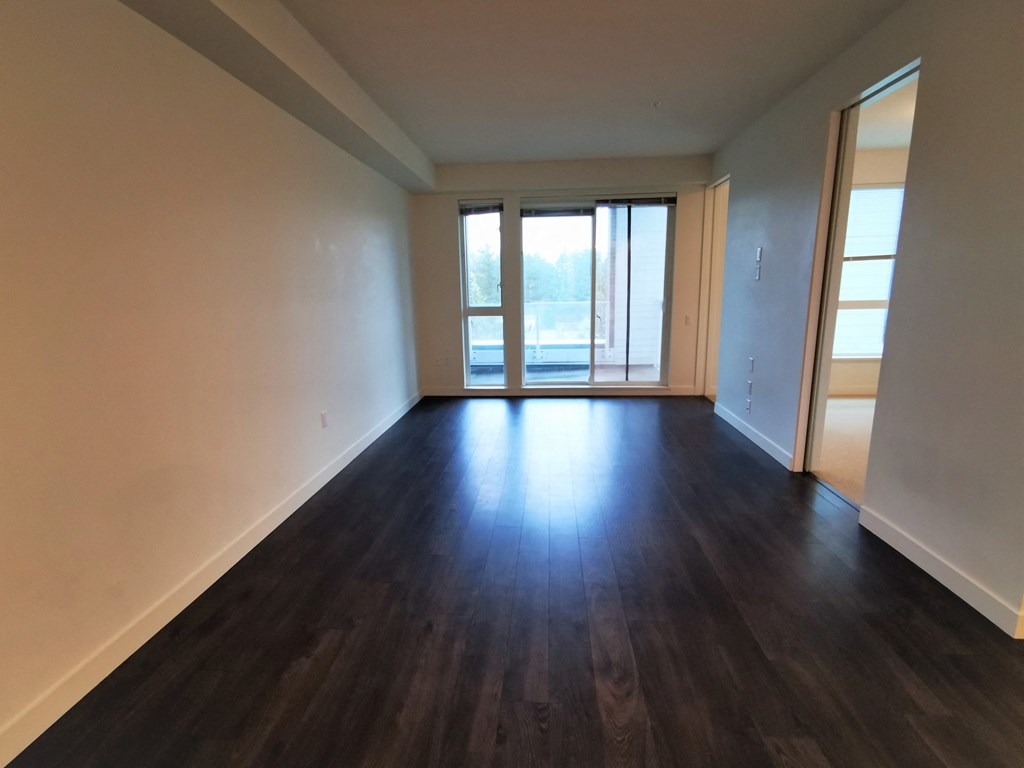an empty living room with hardwood floors and a window