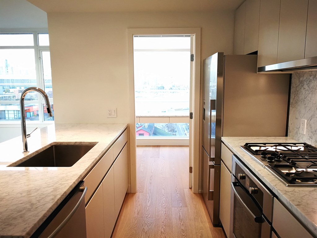 a kitchen with stainless steel appliances and marble counter tops and a window