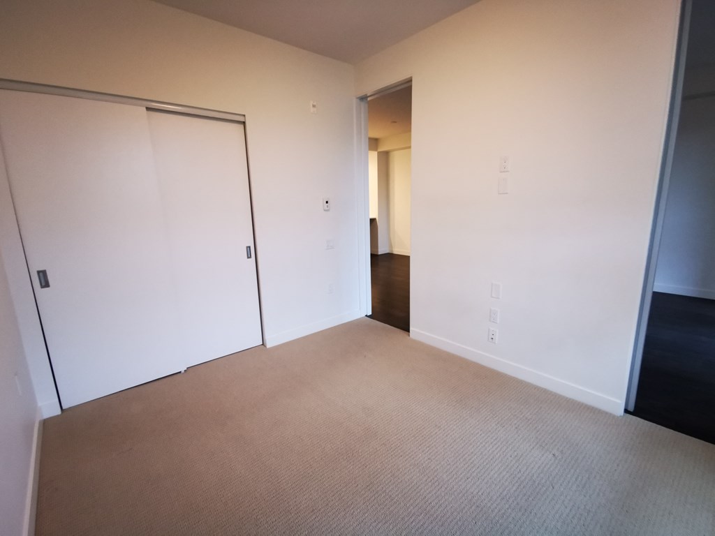 a bedroom with a carpet and a door to a closet