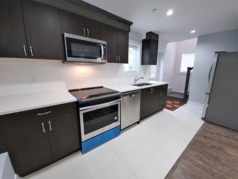 a kitchen with dark cabinets and a stove and a microwave