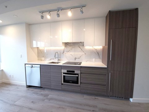 A modern kitchen with a marble backsplash and wooden cabinets.