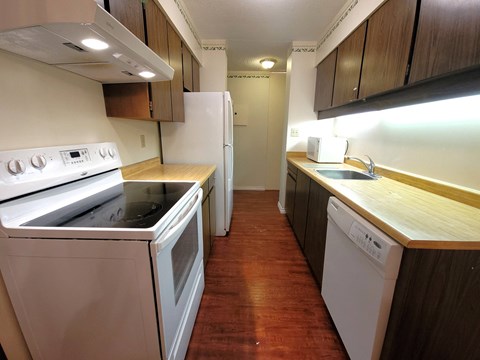 A kitchen with white appliances and wooden cabinets.