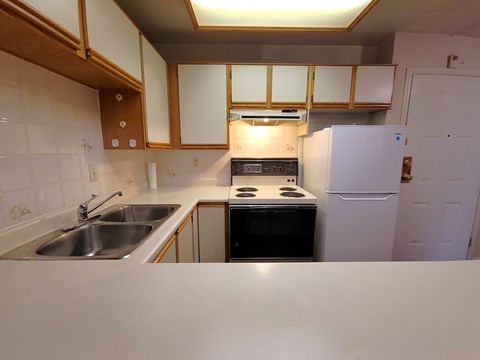 A kitchen with a white refrigerator, stove, and sink.