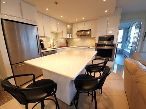 a modern kitchen with a white island and black chairs