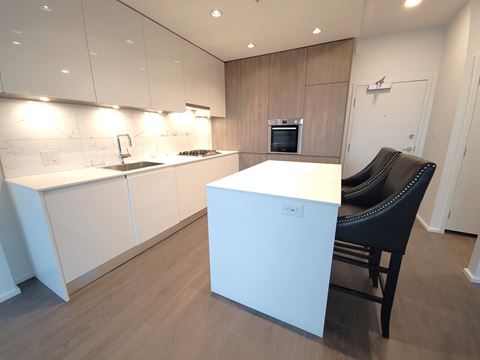 a kitchen with white cabinets and a white island with two black chairs