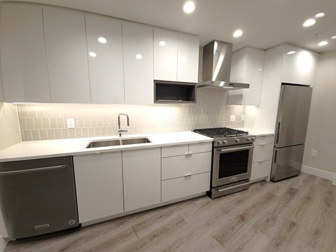 a kitchen with white cabinets and stainless steel appliances and a sink