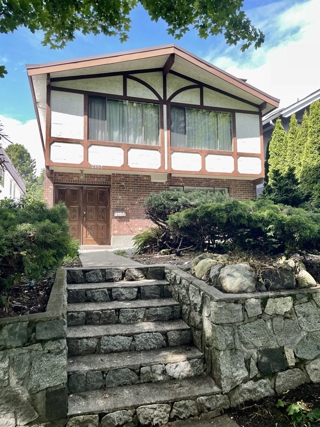 the front of a house with stone steps and a stone retaining wall