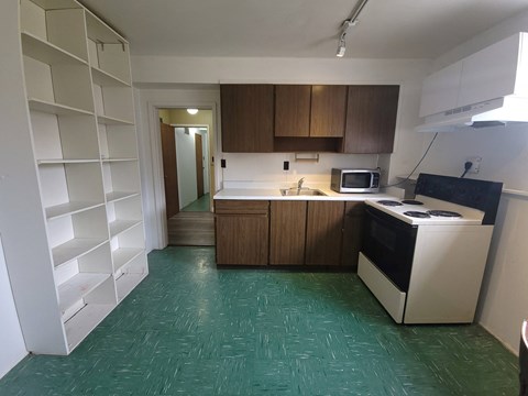 an empty kitchen with a green tile floor and white appliances